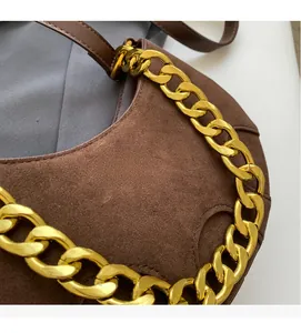 Detail of dark brown suede crescent bag featuring a thick gold chain and stitching