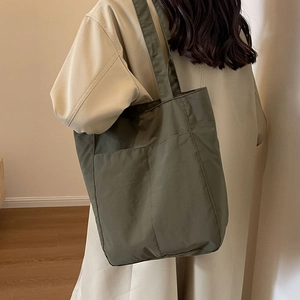 Olive green large capacity nylon tote bag shown in use with a stylish casual outfit