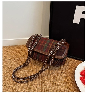 Detail of vintage plaid texture with brown leather trim and golden chain strap