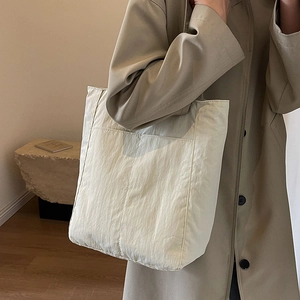 Minimalist creamy nylon tote bag with large front pockets for modern daily commuting