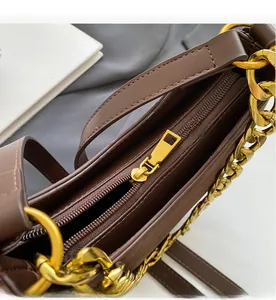Detailed close-up of dark brown vintage saddle bag with gold zipper and chunky chain strap