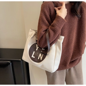 Détail du sac cabas en toile avec patch YLN en cuir et poignée en chaîne métallique