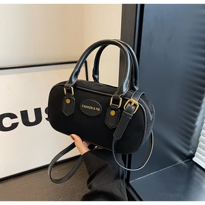 Detail of hand-held black frosted Boston bag with dual handles and gold hardware