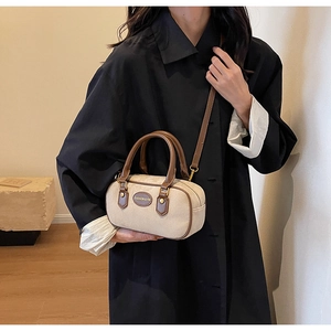 Close-up of beige canvas pillow bag with brown leather handles and shoulder strap detail