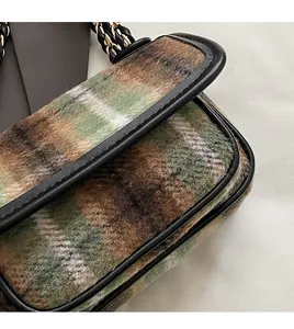 Detailed view of vintage green and brown plaid wool fabric with black leather trim