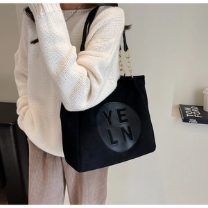 Détail du grand sac cabas noir mat avec empiècement cuir et chaîne dorée sur mannequin
