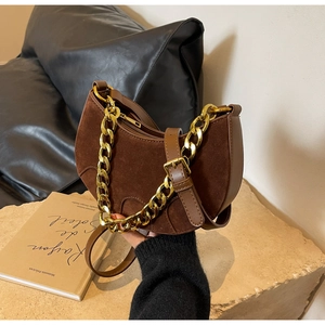 Detail of brown suede saddle bag with chunky gold chain and leather shoulder strap