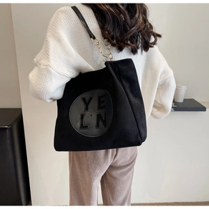 Détail du sac cabas noir mat avec logo YELN et bandoulière en chaîne dorée et cuir