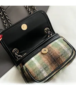Detail view of gold metal magnetic clasp and check pattern wool on a crossbody bag