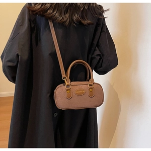 Close-up of brown suede bowling bag with dual handles and adjustable crossbody strap