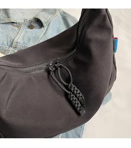 Detail of smooth double zipper with braided rope pulls on black nylon shoulder bag