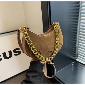 Detail of a brown suede crescent bag featuring a bold chunky gold metal chain strap