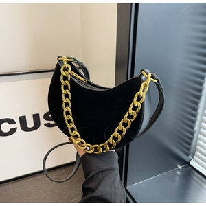 Detailed close-up of matte black hobo bag with gold chain and leather shoulder strap