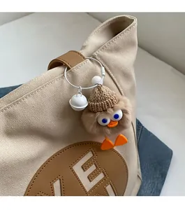 Close-up of a cute plush duck pendant with brown knit hat on a canvas tote bag