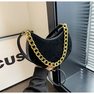 Detail of black suede hobo bag with bold gold chain and smooth leather patchwork