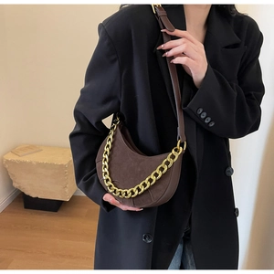 Close-up of matte dark brown saddle bag with a decorative gold metal chain strap