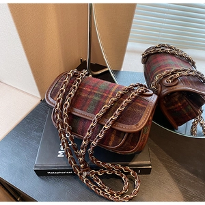 Close-up of retro plaid tweed handbag with leather trim and gold chain shoulder strap