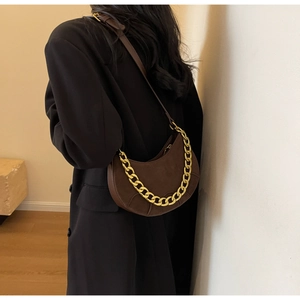 Detail of dark brown matte leather crescent bag with decorative matte gold chain strap