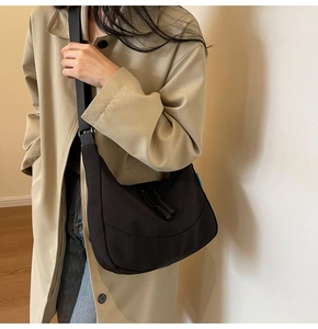 Detail of black nylon crescent hobo bag with adjustable wide strap on casual outfit