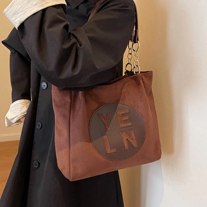 Sac cabas en daim marron avec écusson en cuir et bandoulières en chaîne métal