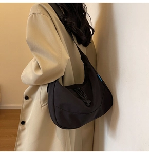 Detail of black nylon crescent shoulder bag with blue tag and adjustable strap