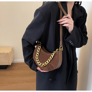 Detailed macro view of brown frosted suede saddle bag with golden chain and leather piping