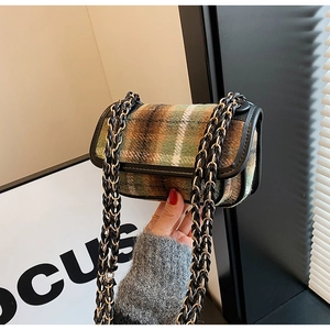 Close-up of green tweed crossbody bag with black leather trim and chain strap