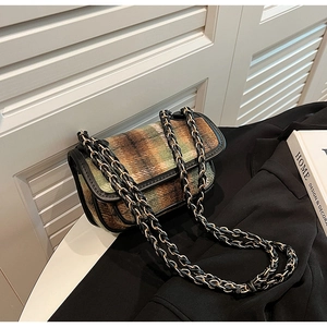 Detail of green plaid wool fabric texture and black leather trim on vintage crossbody bag