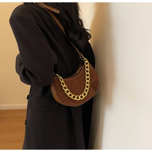 Detail of brown suede crescent saddle bag featuring gold chain and leather shoulder strap