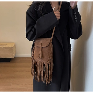 Vue détaillée du sac bandoulière en daim marron avec pompons et bandoulière en cuir