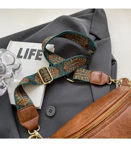 Brown lychee leather fanny pack featuring a wide geometric woven shoulder strap and gold hardware