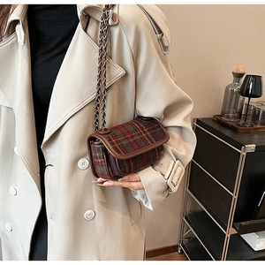 Close-up of vintage plaid chain bag on a beige coat, highlighting texture and leather trim