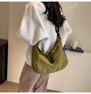 Detailed view of olive green nylon crescent bag with woven zipper pullers and blue side label
