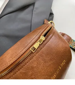 Macro detail of brown leather bag showing gold zipper and fashion text print