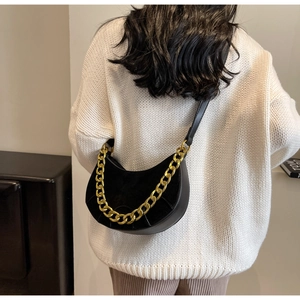 Detail of black semi-circle hobo bag featuring matte finish and gold chain strap