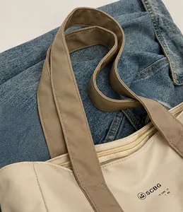 Dettaglio della borsa tote in nylon con manici rinforzati e chiusura con cerniera