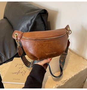 Close-up of vintage brown leather waist bag with colorful bohemian wide shoulder strap