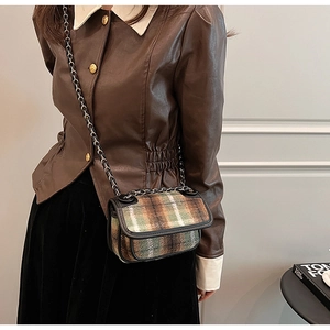 Detail of retro green and brown plaid flap bag with black chain strap on a model