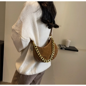 Detail view of brown matte suede saddle bag with chunky gold chain strap on a model