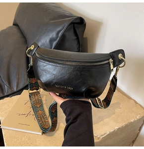 Close-up of black PU leather waist bag with vintage patterned wide strap and gold hardware