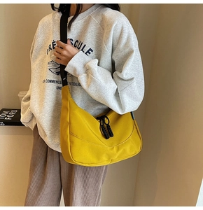 Detail of yellow nylon crescent bag featuring black drawstring and adjustable strap