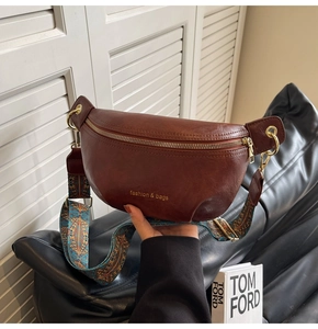 Detail of dark brown leather fanny pack featuring a bohemian wide strap and golden hardware