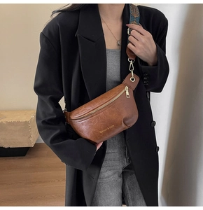 Brown leather crossbody bag detail featuring a vintage bohemian wide strap and gold zipper