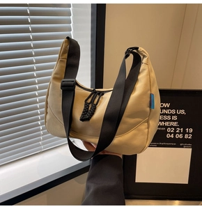 Detail of beige nylon crossbody bag with braided double zipper pulls and black wide strap