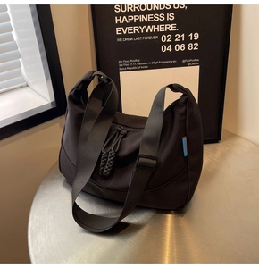 Close-up of black nylon crossbody bag with adjustable strap and textured zipper detail