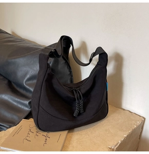 Close-up of black nylon crescent bag featuring wide strap with adjustable buckle and tag