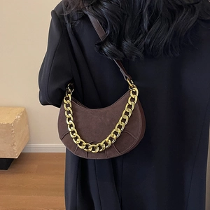 Brown matte leather hobo bag with gold chain strap on woman in black blazer
