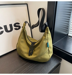 Detail of olive green nylon crescent bag featuring black rope zipper and woven strap