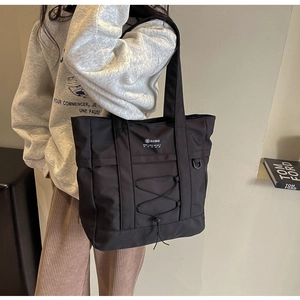 Dettaglio della borsa tote nera in nylon con coulisse e logo bianco stampato
