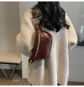 Details der braunen Leder-Gürteltasche mit breitem Jacquard-Gurt und goldenem Reißverschluss